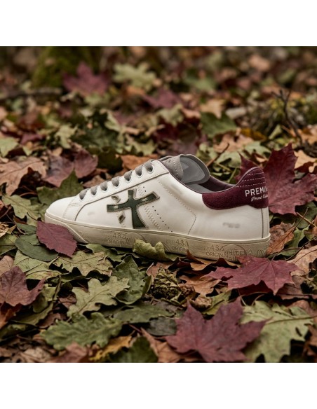 Premiata Steven print edition logo verde desgastado y talonera en ante granate dos pies sobre hojas vista desde atras
