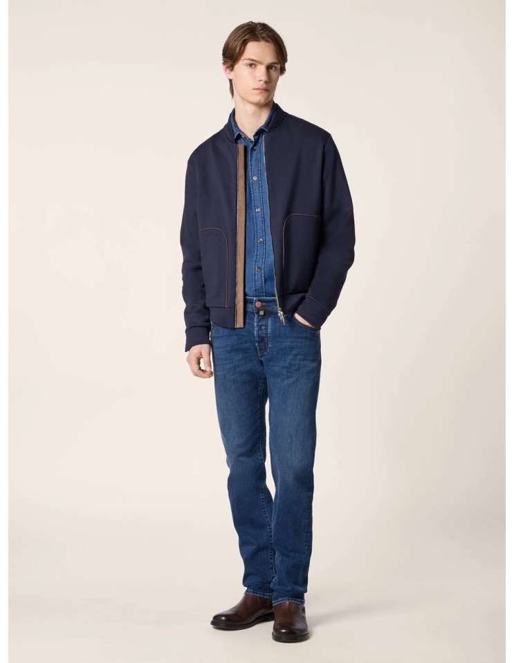 Pantalones vaqueros Bard en denim elástico azul medio con lavado vintage vista frontal en maniquí con cazadora azul