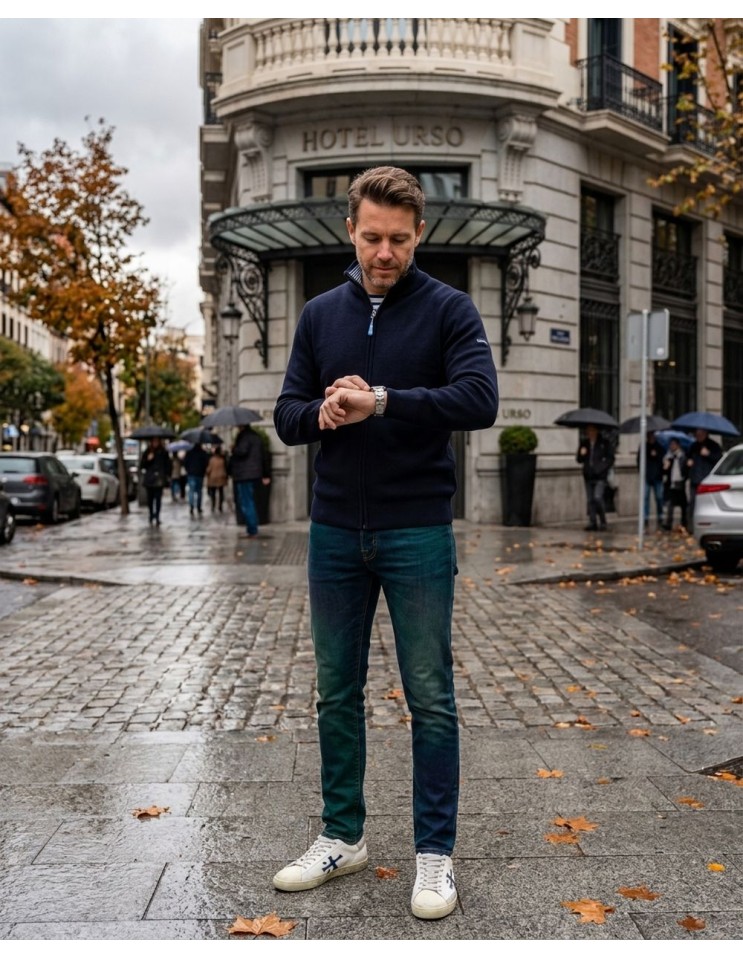 Saint James Cárdigan Creggan color azul marino puesto en un hombre mirando el reloj, con vaqueros y zapatillas blancas