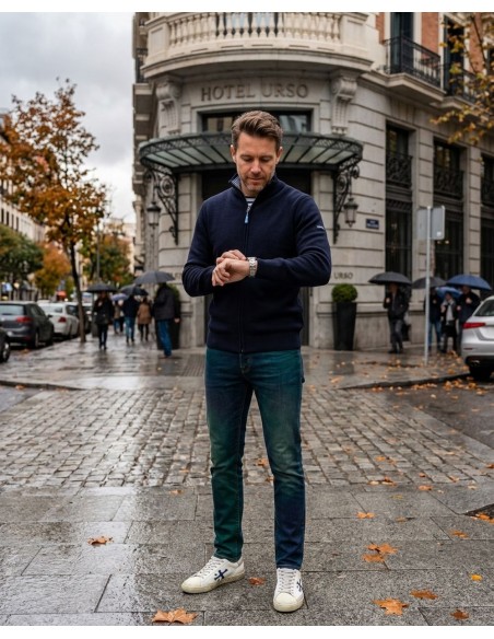 Saint James Cárdigan Creggan color azul marino puesto en un hombre mirando el reloj, con vaqueros y zapatillas blancas