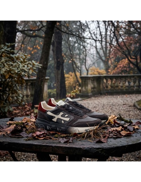 Premiata Mick negro gris y talonera roja vista otoñal, sobre base de piedra y hojas